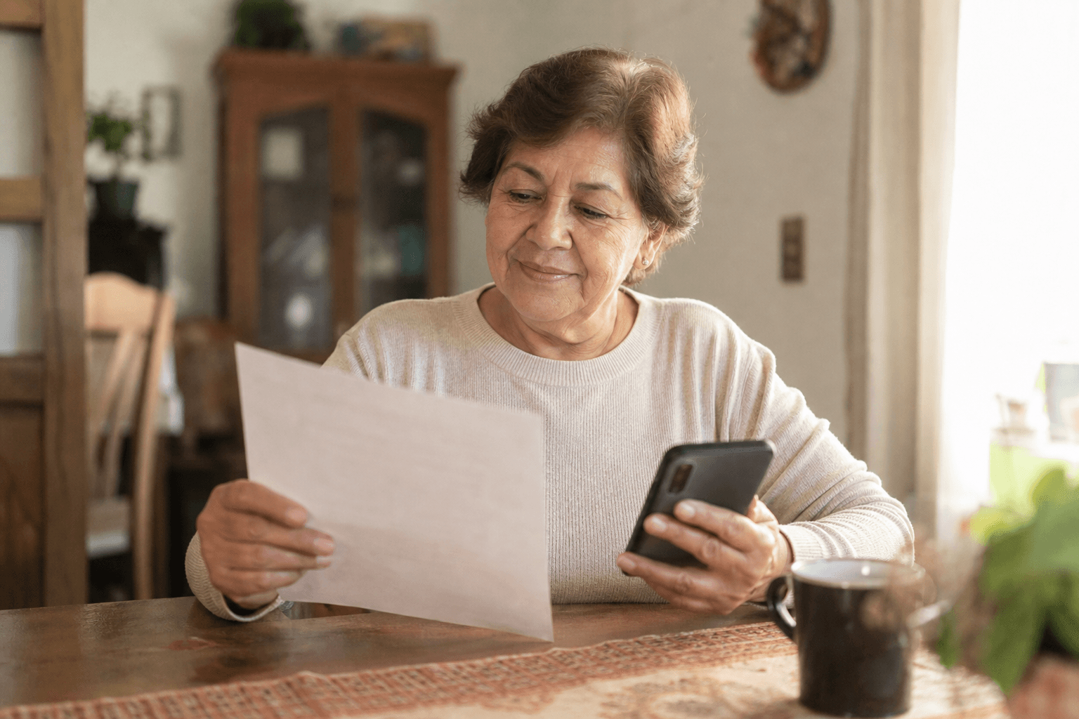 Adulto mayor hispano revisando con calma información sobre Medicare y gastos funerarios en casa — Asegurables.com
